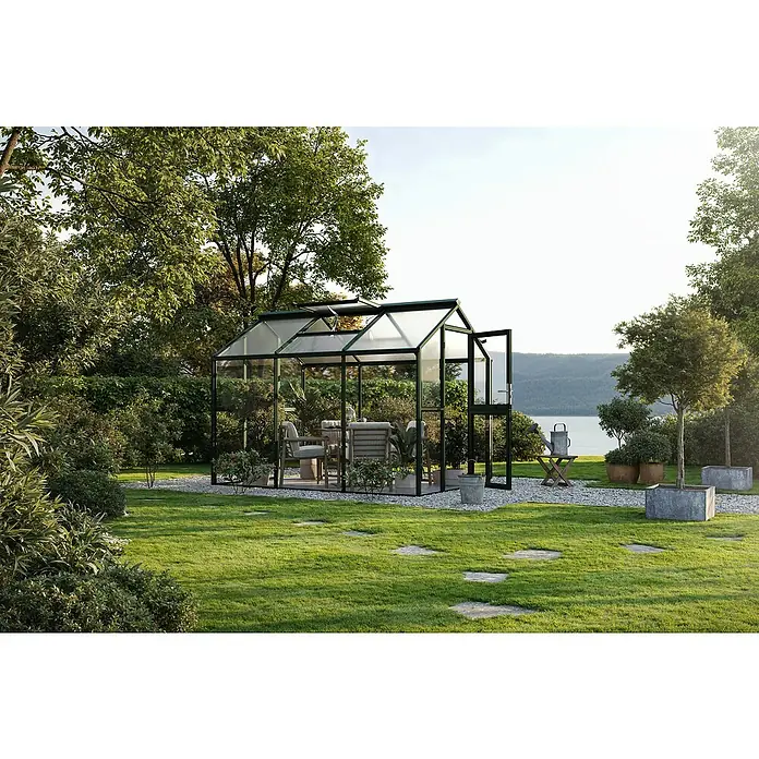 KGT Gewächshaus Galant III - Außenmaß inkl. Dachüberstand (B x T): 216 x 308 cm, Material Seitenwand: Glas, 4 mm, Tannengrün - Das Bild zeigt ein Gewächshaus im Freien, das einen ruhigen, grünen Garten mit bequemen Sitzmöbeln im Inneren ergänzt.