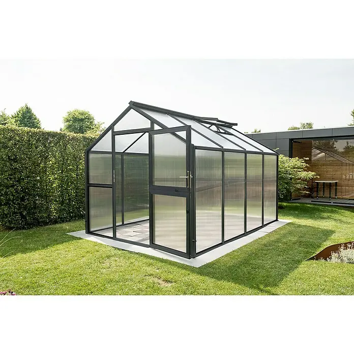 KGT Gewächshaus Novum IV - Außenmaß inkl. Dachüberstand (B x T): 273 x 408 cm, Material Seitenwand: Kunststoff, 10 mm, Anthrazit-Grau - Ein modernes Gewächshaus mit geöffneter Tür, umgeben von gepflegtem Rasen und Grünpflanzen. Optimal für Gartenliebhaber.