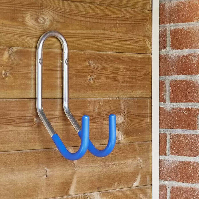 Mottez Gancho de pared para bicicletas - Diámetro: 16 mm, Acero, Plateado - Gancho de almacenamiento de metal plateado con puntas de goma azules, montado en una pared de madera.