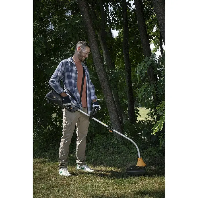 Alpina Recortabordes eléctrico ATR 1.0 EJ - 1.000 W, Ancho de corte hilo: 37 cm - Un hombre usa un cortabordes en el jardín para cortar el césped. El cortabordes es bien visible.
