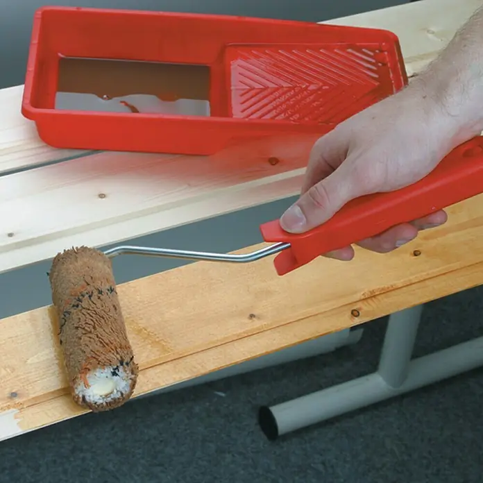 Lehnartz Holzschutzroller Komplett-Set - 4 -tlg., Geeignet für: Lasuren - Nahaufnahme von Lackierarbeiten mit einem Farbroller und roter Farbwanne, die auf einem Holzbettgestell verwendet werden.