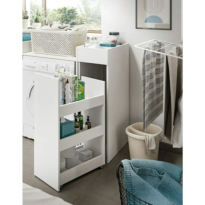 xonox.home Free Waschmaschinenregal - L x B x H: 60 x 95 x 101 cm, Weiß - Aufnahme eines Badezimmers mit einem weißen, schmalen Rollwagen mit drei Regalen, gefüllt mit Reinigungsmitteln und Toilettenartikeln.