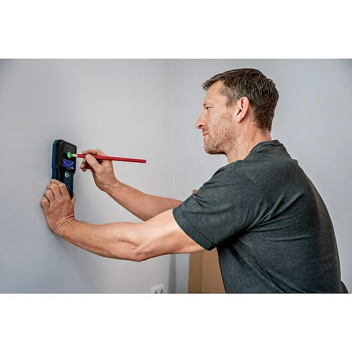 Bosch Professional Ortungsgerät GMS 120-27 - Erfassungstiefe: Max. 120 mm NE-Metalle - Ein Mann benutzt den Bosch Ortungsgerät, um die Wand nach verborgenen Strukturen zu scannen und markiert die Position mit einem Bleistift.
