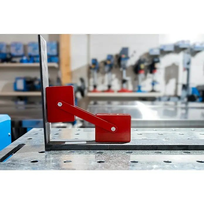 Güde Schweiß-Winkelmagnet - 1 Stk. - Magnetischer Schweißwinkelhalter in Rot fixiert zwei Metallstücke im rechten Winkel auf einem Tisch.