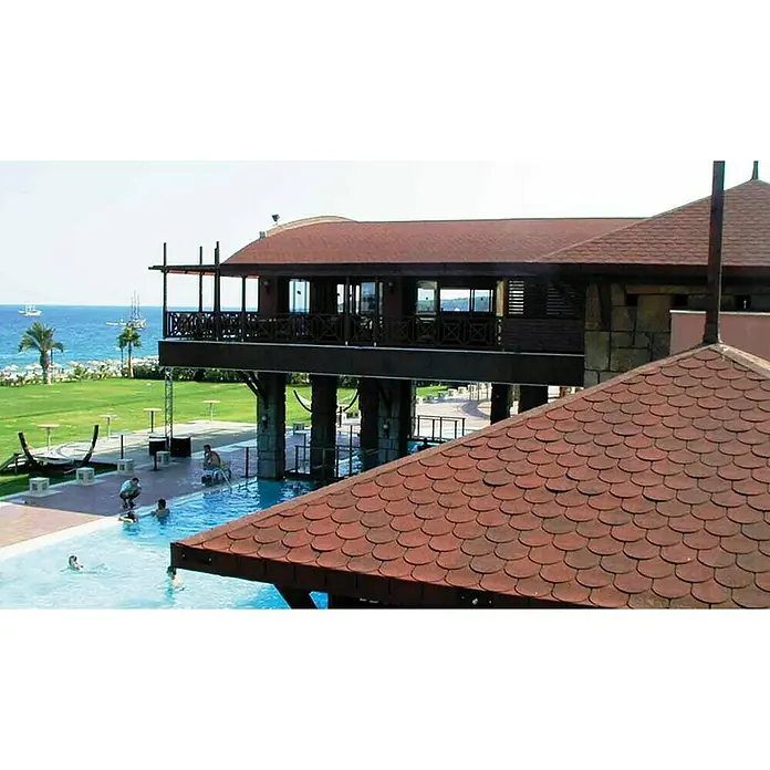 Onduline Tégola cola castor - Rojo - Una vista panorámica de un lujoso resort que ofrece un techo de tejas de diseño intrincado y una piscina ideal para la relajación.