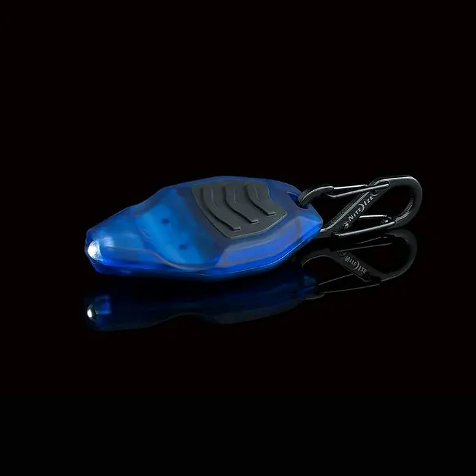 Linterna Nite Ize - LED, 16 lx - Primer plano de una luz LED azul Nite Ize con un mosquetón, destacando su tamaño miniatura y funcionalidad para llevar a diario.