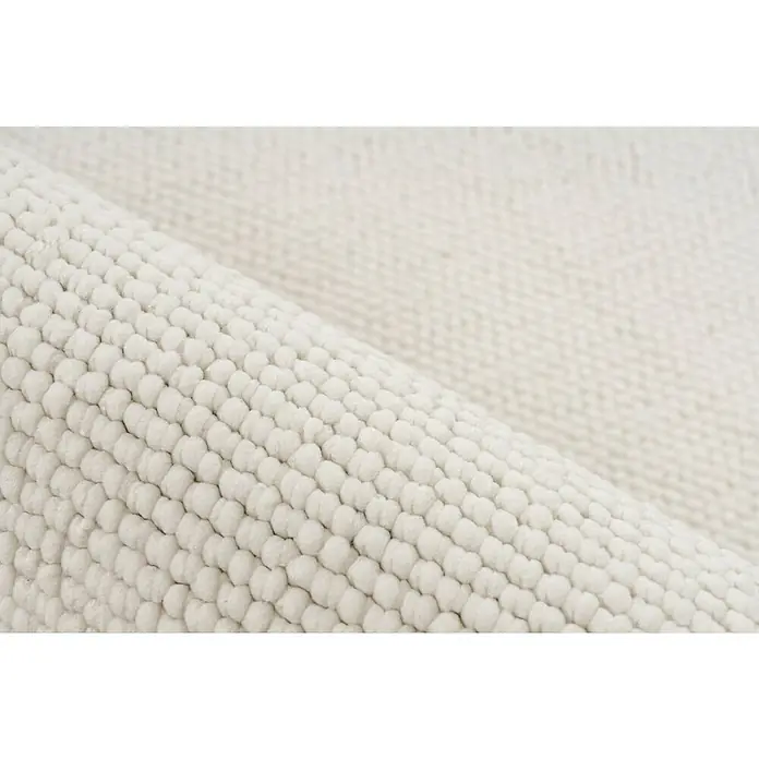 Fransenteppich Tunis 400 - Ivory, 150 x 80 cm, 100 % Polyester - Nahaufnahme eines gerollten, weißen Chenille-Badteppichs, der seine weiche Textur und hochwertige Verarbeitung hervorhebt.