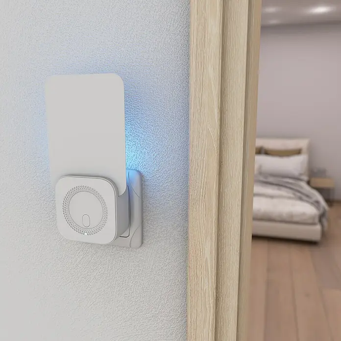 Windhager Klebefalle Fluginsekten UV - Weiß - Eine Nahaufnahme eines weißen, an der Wand befestigten Nachtlichts mit blauem Lichtschein in einem modernen Schlafzimmer.