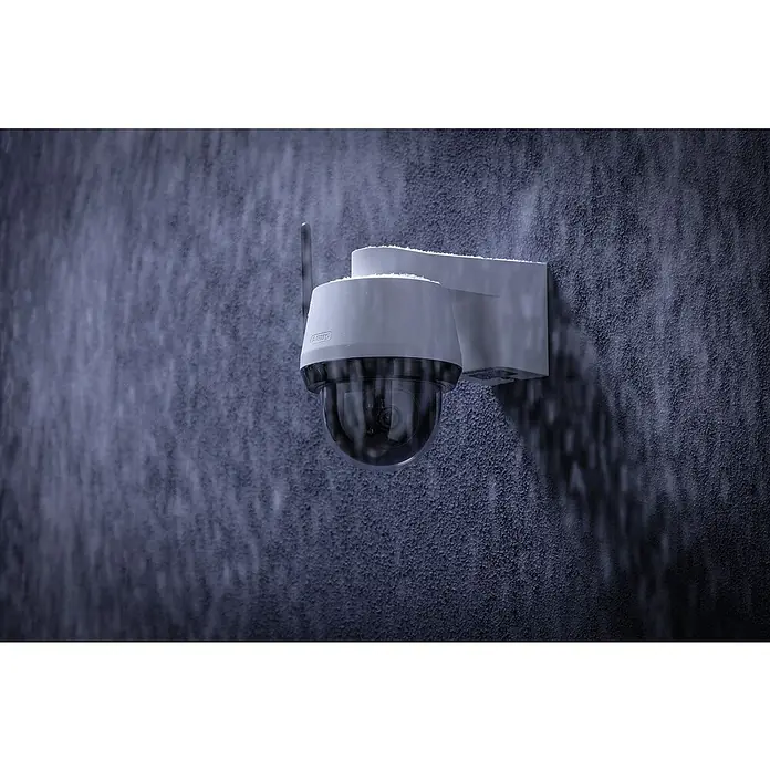 Abus Überwachungskamera Smartlook PPIC52520 WS - Auflösung: 4K Ultra HD/HDR, Weiß - Eine weiße ABUS Überwachungskamera ist an einer strukturierten Wand befestigt, die im Regen steht. Die Kamera ist wetterfest.