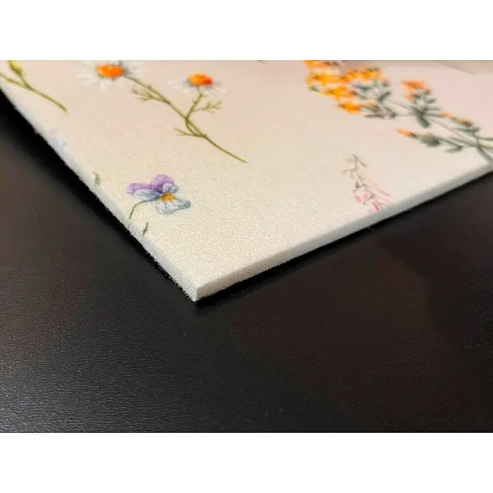 Bariperfil Panel acústico decorativo Acoustic Wall Flores - 260 x 60 x 0,65 cm, Beige - Primer plano de un tablero de espuma grueso y cuadrado con un estampado floral sobre una superficie negra lisa.
