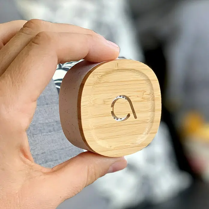 Avidsen Funk-Türgong Drahtlos Bamboo für USB-Anschluss - Grau, Bambus, Reichweite ca.: 100 m - Nahaufnahme eines Holzkästchens mit einem "a"-förmigen Ausschnitt, gehalten in einer Hand. Das Produkt ist ein schlichtes, natürliches Designelement.