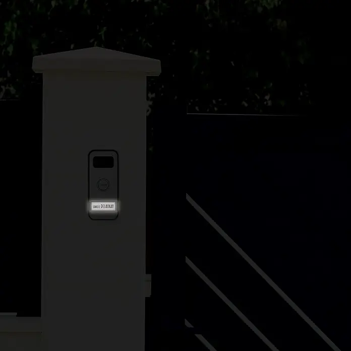 Avidsen Türklingel mit Kamera Prima kabelgebunden - Silber, 800 x 480 Pixel - Das Bild zeigt eine moderne Klingelanlage mit dem Namen "Famille Delaunay" in der Dunkelheit, die am Eingangstor eines Hauses angebracht ist.