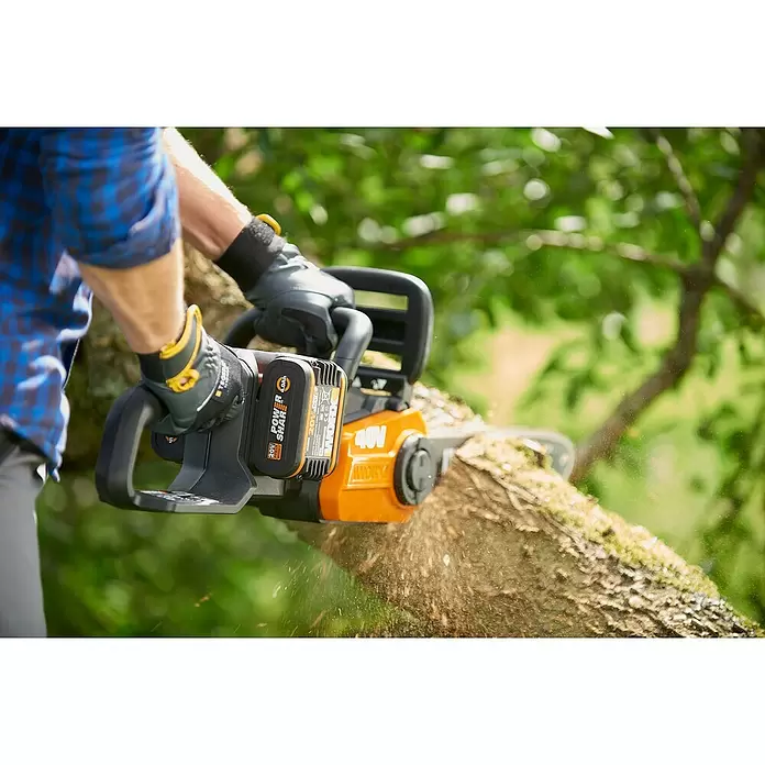 Worx PowerShare 20V Akku-Kettensäge WG384E.9 - Akkuspannung: 40 V, Li-Ionen, Ohne Akku, 35 cm - Person schneidet Ast mit oranger und schwarzer 40V WORX Akku-Kettensäge.
