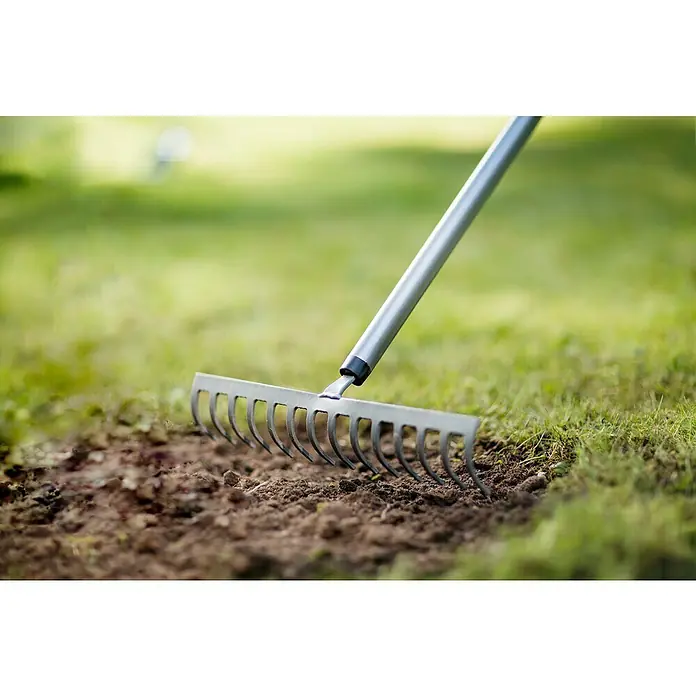 Fiskars Ergonomic Gartenrechen - Material Gerätekopf: Borstahl, 1 Stk. - Nahaufnahme eines Metallrechens, der zum Glätten des Bodens in einem Garten verwendet wird. Ideal für Gartenarbeiten und Landschaftsbau.