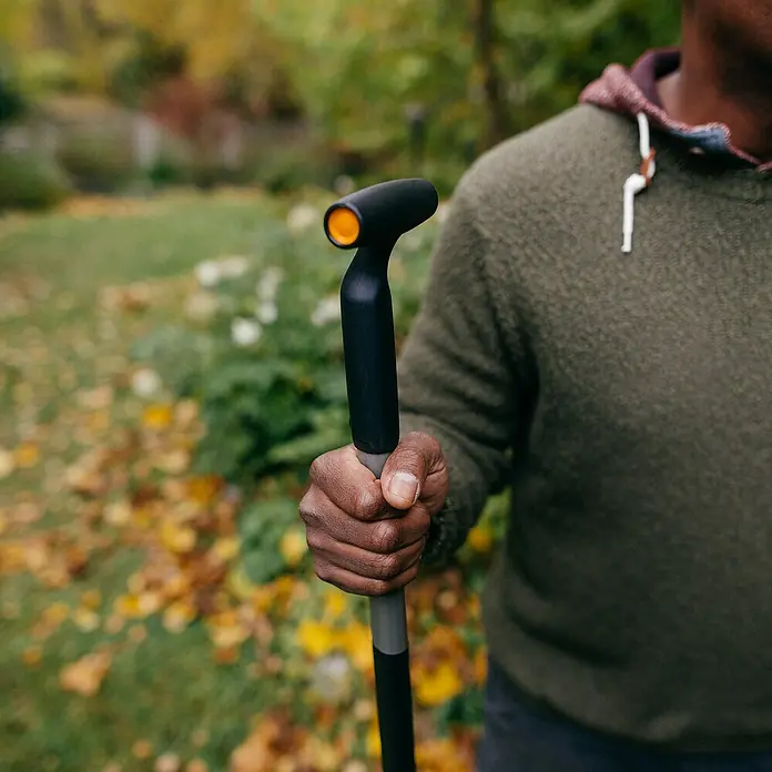 Fiskars Ergonomic Laubschaufel - Material Gerätekopf: Kunststoff, 1 Stk. - Nahaufnahme einer Fiskars Unkrautwurzelentfernung, die von einer Person im Garten gehalten wird.