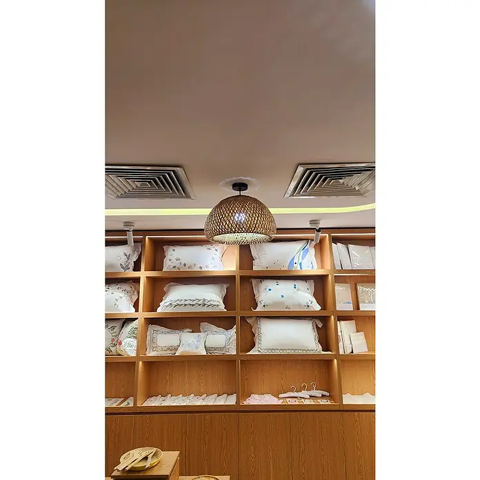 Tween Light Lámpara colgante redonda Bambú - Ø x Al: 30 x 20 cm, Bambú - Estantes que muestran almohadas y una lámpara decorativa en el centro que emite una luz cálida. Las almohadas están bien apiladas.