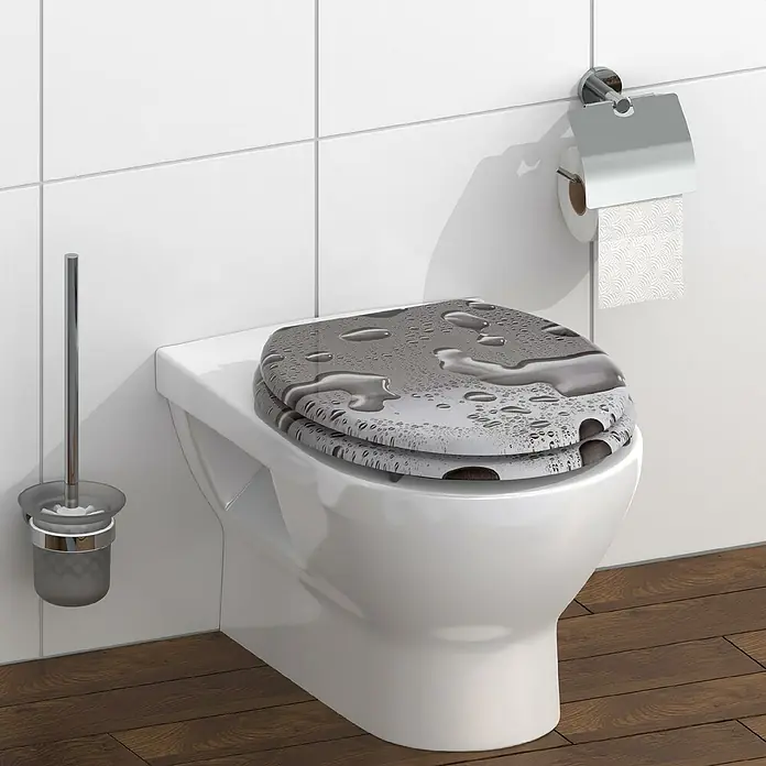 Schütte WC-Sitz Grey Steel - MDF, Grau, Ohne Absenkautomatik - Das Bild zeigt eine moderne Toilette mit einem Toilettensitz im Wassertropfen-Design, eine Toilettenbürste und einen Toilettenpapierhalter in einem Badezimmer.