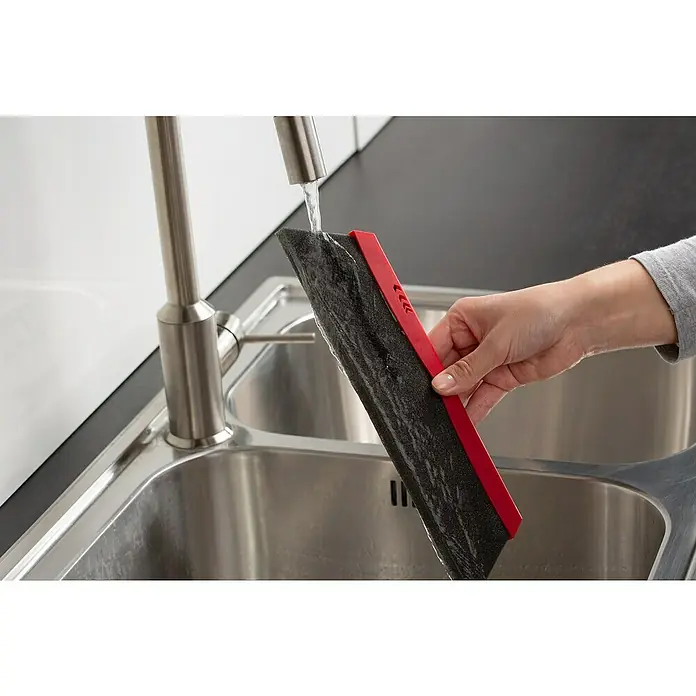 Vileda Superfeger Straßenbesen Antistaub Duactiva - Mit Teleskopstiel, Material Borsten: Synthetik, Breite Besen: 35 cm - Nahaufnahme eines Spültischabstreifers mit rotem Griff, der unter einem Wasserhahn in einem Spülbecken gehalten wird. Ideal zum Reinigen von Oberflächen.