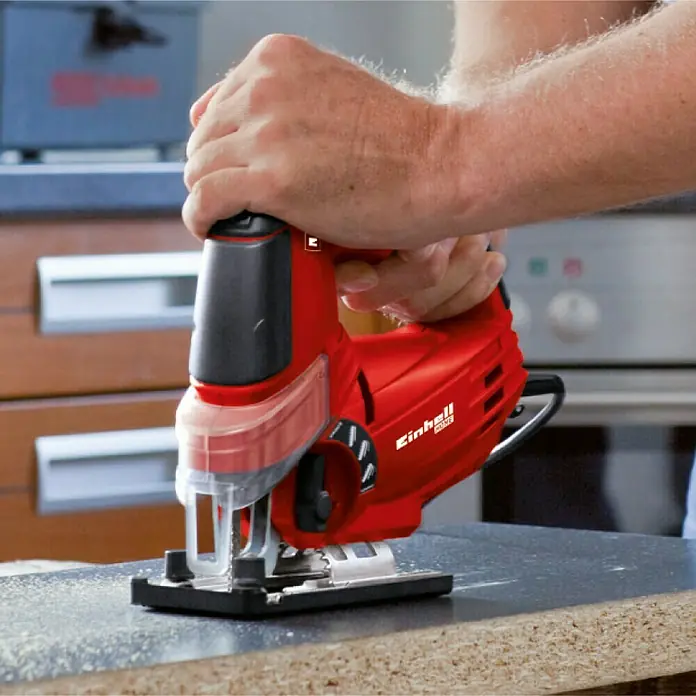 Einhell Power X-Change 18V Akku-Pendelhubstichsäge TE-JS 18/80 Li-Solo - 18 V, Ohne Akku, 0 /min - 2.400 /min - Nahaufnahme einer Einhell Stichsäge in roter Farbe beim Sägen eines Holzstücks. Die Stichsäge wird von einer Person bedient.