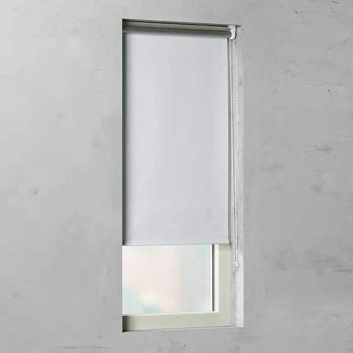 Rollo Basic - B x H: 60 x 175 cm, Weiß, Uni, Verdunkelnd - Eine minimalistische, weiße Fensterrollo, die teilweise heruntergelassen ist, hängt vor einem Fenster in einer grauen Wand.