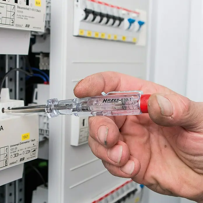 Hazet Spannungsprüfer 839-1 - Klingenlänge: 40 mm - Ein Elektriker prüft mit einem HAZET 839-1 Spannungsprüfer eine elektrische Anlage. Das Werkzeug ist ideal für sichere Strommessungen.