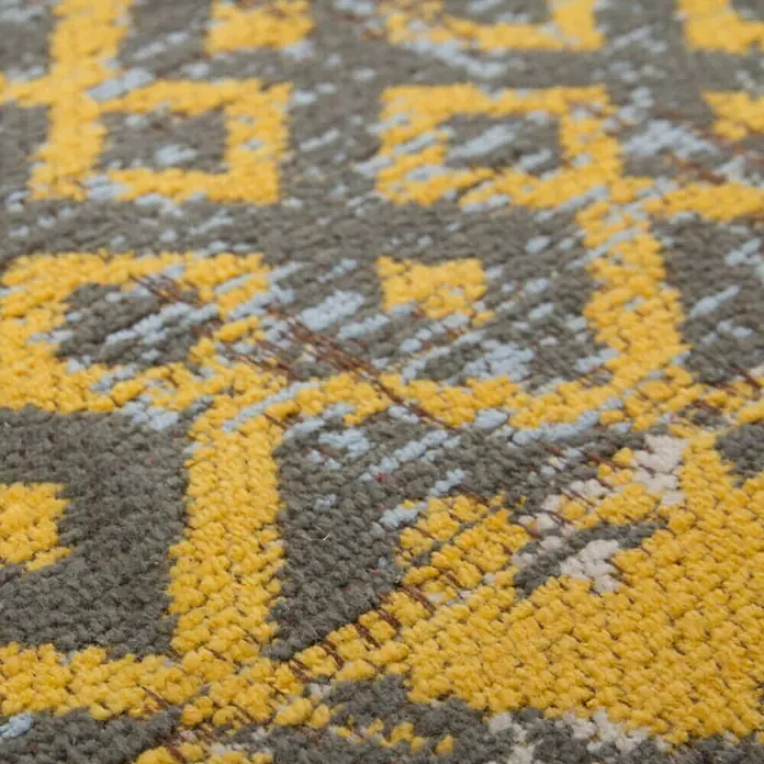 Kayoom Flachgewebeteppich Jacquard - Gold, 150 x 80 cm, 100 % Baumwolle - Nahaufnahme eines Teppichs mit geometrischem Muster in Gelb-, Grau- und Blautönen. Die Textur ist dicht und detailliert.