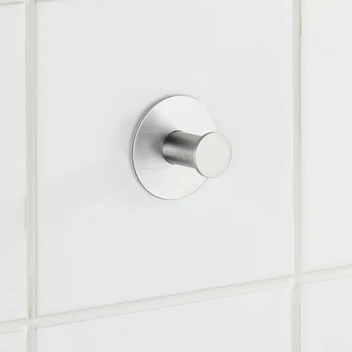 Wenko Handtuchhaken Celano - 1 Stk., Edelstahl, Matt - Naheaufnahme eines einzelnen silbernen Kleiderhakens an einer weißen, gefliesten Wand.