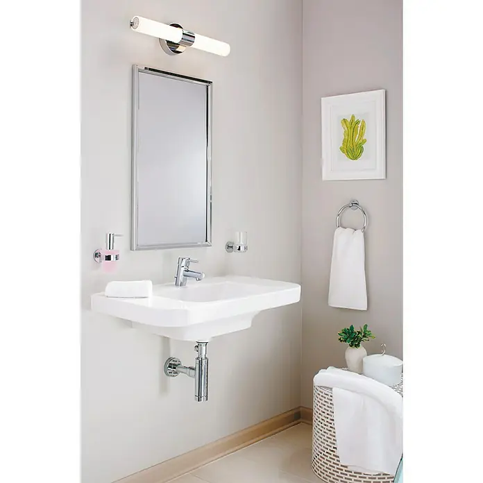 Grohe Essentials Handtuchring - Chrom, Glänzend - Ein Badezimmer mit einem eleganten Waschbecken, einem Spiegel und einer stilvollen Lampe, die eine entspannende Atmosphäre schaffen.