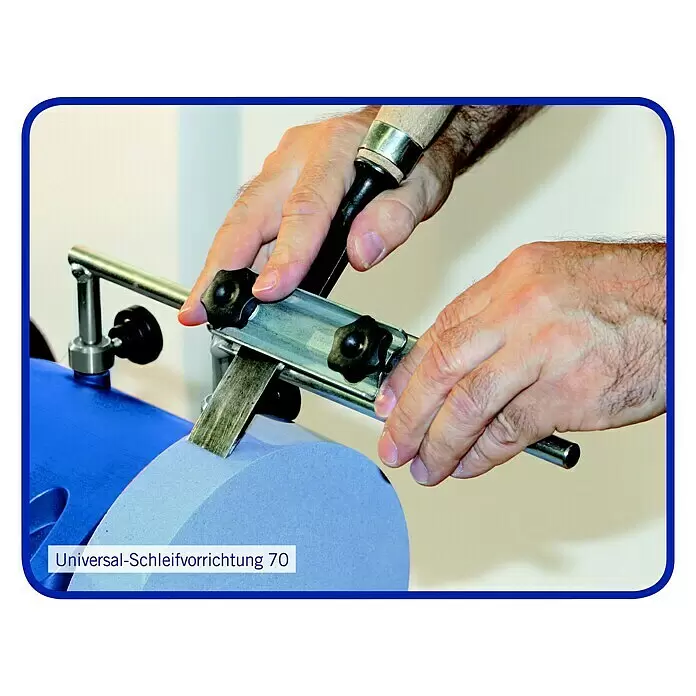 Scheppach Afiladora al agua TiGer 2000 S - 120 W - Una persona afila un cincel con una plantilla universal de afilado 70 metálica sobre una muela abrasiva azul claro.