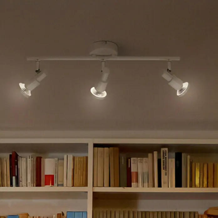 Ledvance Deckenstrahler Spot - 10,2 W, L x B x H: 48,6 x 9 x 15,5 cm, Weiß, GU10, 3 Stk. - Deckenleuchte mit drei Strahlern, die Licht auf ein Bücherregal wirft. Die Strahler sind auf einer weißen Stange montiert.