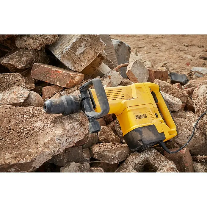 Stanley FatMax Martillo demoledor SFMEH230K-QS - 1.600 W, 15 J, Alojamiento SDS-MAX - Primer plano de un martillo de demolición amarillo Stanley Fatmax sobre una pila de ladrillos.
