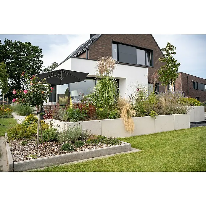 Diephaus Hochbeet - 110 x 100 x 80 cm, Beton, Grau - Blick auf ein modernes Haus mit einem schön gestalteten Garten, der mit üppigen Pflanzen und stilvollen Betonelementen aufgewertet ist.