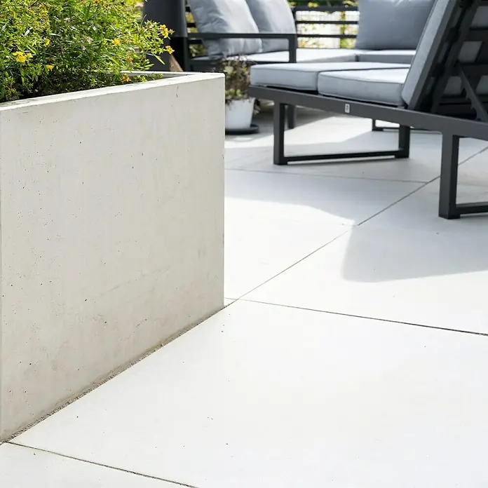 Diephaus Hochbeet - 210 x 100 x 80 cm, Beton, Grau - Nahaufnahme eines quadratischen Betonpflanzgefäßes mit üppigem Grün, das einen modernen Außenbereich mit stilvollen Gartenmöbeln betont.