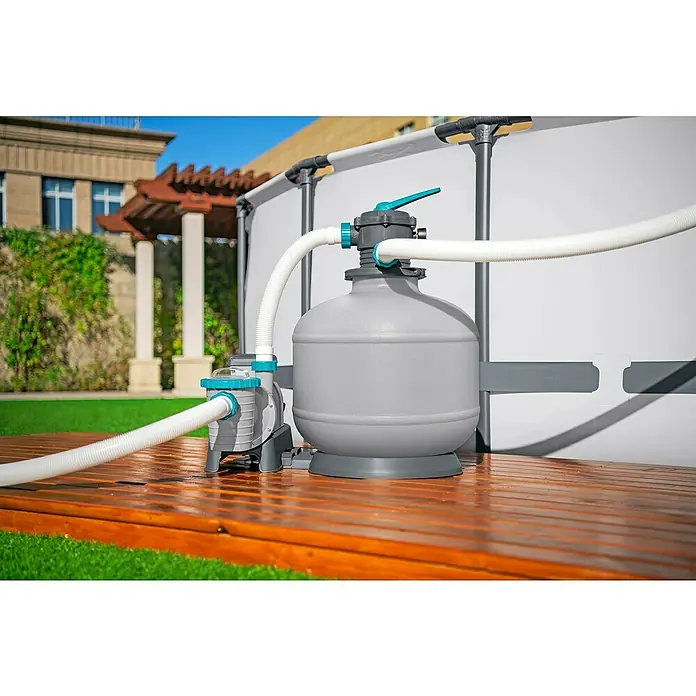 Bestway SandfilteranlageFilterleistung: 7.570 l/h, Passend für Poolgröße: 60.500 l - Nahaufnahme einer Poolpumpe und eines Filtersystems auf einer Holzterrasse im Freien, mit Fokus auf die Poolreinigungsanlage.