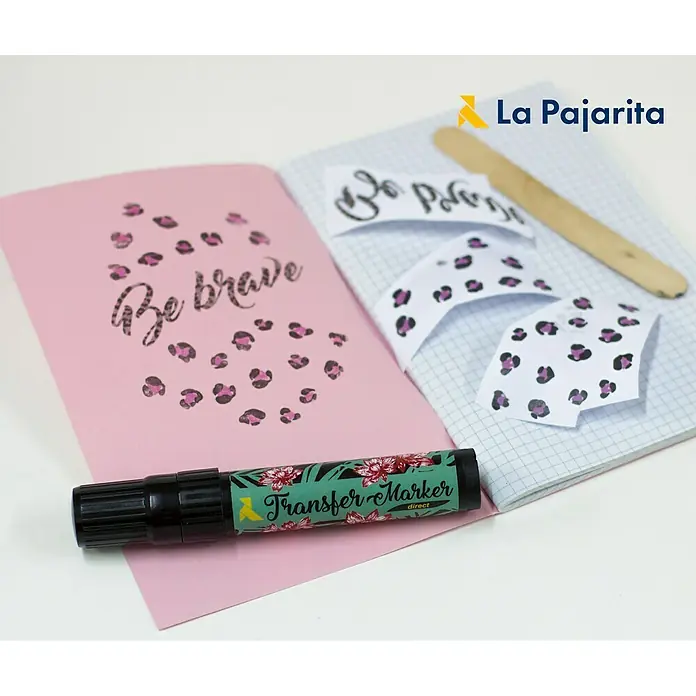 La Pajarita Marcador para ropa Transfer market direct - Incoloro - Primer plano de un rotulador de transferencia La Pajarita, utilizado para transferencias de telas, junto con un cuaderno y una plantilla artesanal.