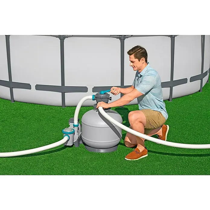 Bestway SandfilteranlageFilterleistung: 7.570 l/h, Passend für Poolgröße: 60.500 l - Ein Mann installiert einen Bestway Sandfilter für einen Frame Pool. Der Filter und die Schläuche sind auf grünem Rasen platziert.