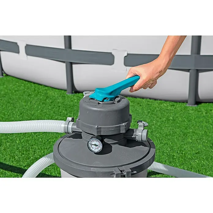 Bestway Sandfilteranlage - Filterleistung: 2.082 l/h, Passend für Poolgröße: 16.600 l - Eine Person bedient den Hebel eines Poolfilters, wobei der Filter und ein Teil des Pools im Hintergrund zu sehen sind.