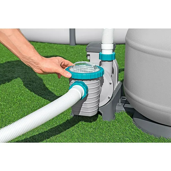 Bestway SandfilteranlageFilterleistung: 7.570 l/h, Passend für Poolgröße: 60.500 l - Eine Person hantiert mit einem grauen Poolfilter, der grüne Akzente hat und an einen weißen Poolschlauch angeschlossen ist.