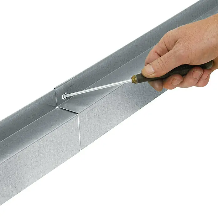 Bellissa Rasenkante Comfort - 118 x 9 cm, Metall, Verzinkt, Mähkante - Eine Hand verwendet einen Schraubendreher, um einen grauen Kabelkanal zu bearbeiten. Das Werkzeug dient zur Montage.