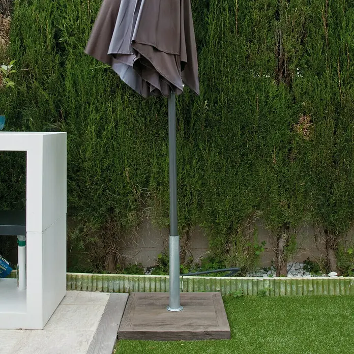 Base de parasol plana - 50 x 50 cm - Primer plano de un parasol gris cerrado con soporte en un patio. El parasol ofrece una sombra agradable.