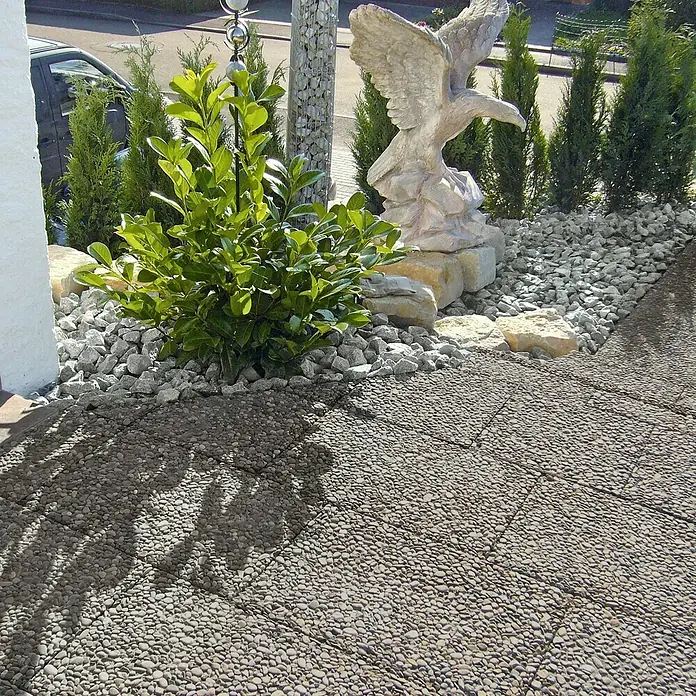 EHL WaschbetonplatteGrau, 40 x 60 x 4 cm - Außenaufnahme eines dekorierten Gartenbereichs mit einer Adlerstatue, Pflanzen und grauen Kieseln auf dem Boden.