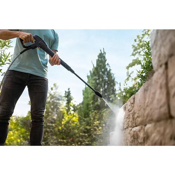 Kärcher Hochdruckreiniger K 7 WCM Pure Flex Home - 3.000 W, Max. Druck: 180 bar, Fördermenge: 600 l/h - Eine Person benutzt einen Kärcher Hochdruckreiniger, um eine Steinmauer im Freien zu säubern, wobei der Fokus auf dem Kärcher Gerät liegt.