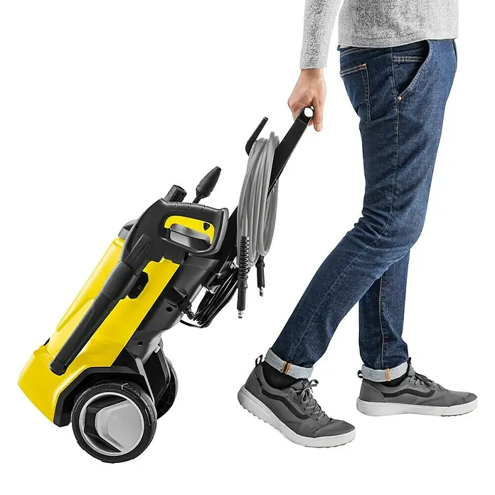 Kärcher Hochdruckreiniger K 7 WCM Pure Flex Home - 3.000 W, Max. Druck: 180 bar, Fördermenge: 600 l/h - Eine gelb-schwarze Kärcher Hochdruckreiniger wird von einer Person gezogen. Der Hochdruckreiniger ist kompakt und hat Räder für einfachen Transport.