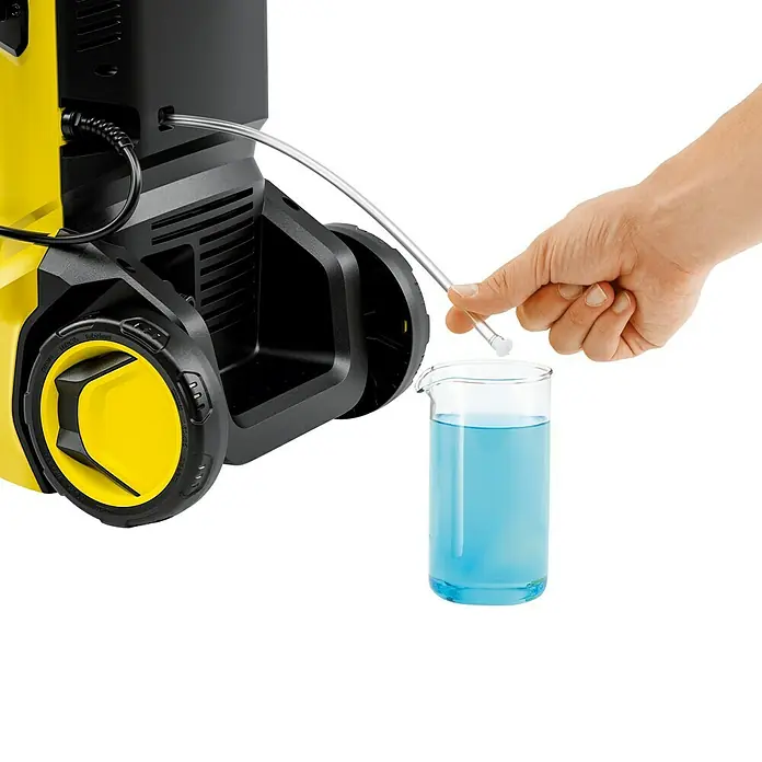 Kärcher Hochdruckreiniger K 5 Pure Flex Home - 2.100 W, Max. Druck: 145 bar, Fördermenge: 500 l/h - Ein gelber Hochdruckreiniger von Kärcher mit einem Schlauch, der in einen Messbecher mit blauer Flüssigkeit gehalten wird.