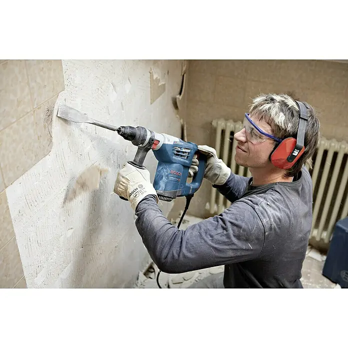 Bosch Professional Kombihammer GBH 4-32 DFR - 900 W, 4,2 J, SDS-Plus-Aufnahme - Ein Bauarbeiter benutzt einen Bosch-Bohrhammer, um Fliesen von einer Wand zu entfernen, wobei er Schutzbrille und Gehörschutz trägt.