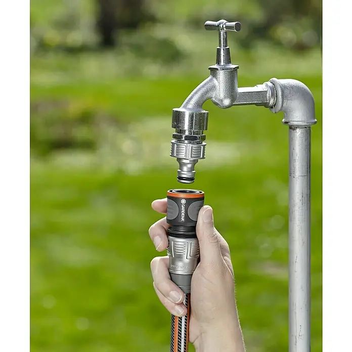 Gardena Schlauchkupplung - Größe: ½″, Ohne Wasserstopp - Gartenschlauch-Anschluss: Eine Hand befestigt einen Gardena-Schlauch an einem Wasserhahn im Garten. Praktisches Zubehör für die Bewässerung.