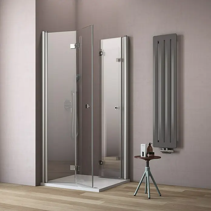 GEO Hit Eckdusche B-E400 - L x B x H: 100 x 90 x 202,2 cm, Beschichtet, Silber, Glasstärke: 6 mm - Duschkabine mit klappbaren Glastüren und chromfarbenen Beschlägen, daneben ein Heizkörper und ein kleiner Tisch.