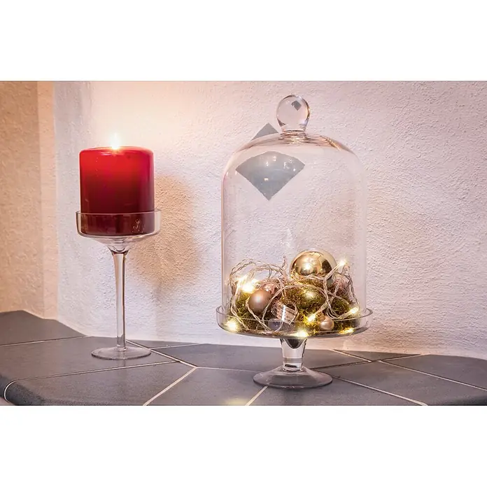Konstsmide LED-Lichterkette - Innen, Lichtfarbe: Warmweiß, Anzahl Leuchtmittel: 10 Stk., Batteriebetrieben - Dekorative Glaskuppel mit Lichtern und Weihnachtskugeln sowie eine rote Kerze auf einem Glasständer.