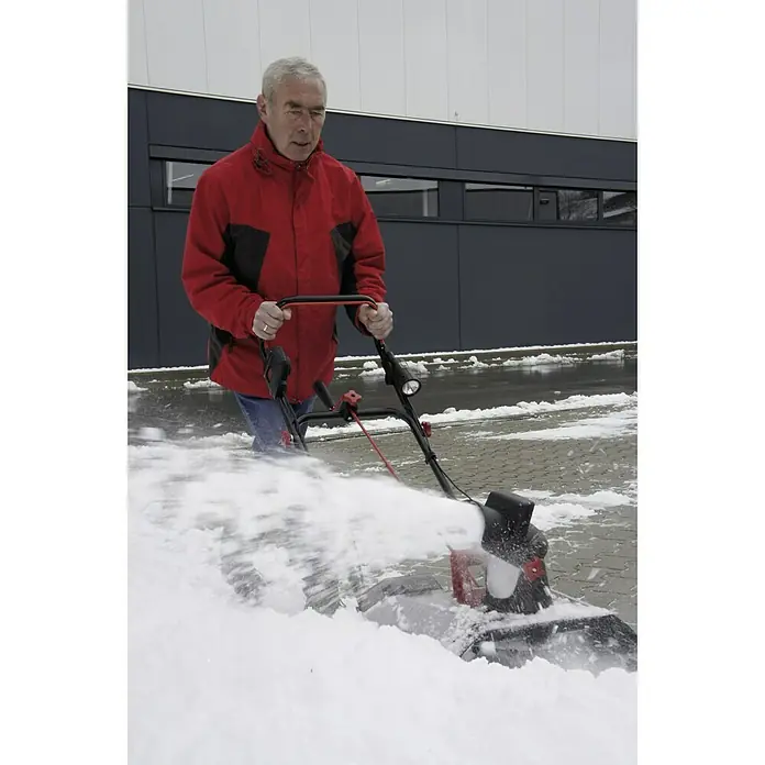 AL-KO 36V Akku-Schneefräse ST4048 - 36 V, Ohne Akku, Arbeitsbreite: 48 cm - Ein Mann benutzt eine Schneefräse, um Schnee von einem Gehweg zu räumen, und die Maschine wirbelt den Schnee auf.
