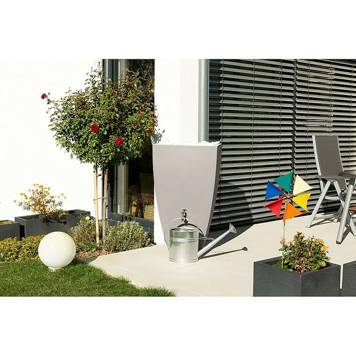 Arves Regenspeicher Modena - 200 l, Taupe - Ein grauer Regenspeicher mit einem silbernen Wasserhahn und einer passenden Gießkanne daneben, in einem idyllischen Garten auf einer Terrasse platziert.